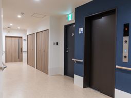 木目調の扉とエレベーターの廊下
