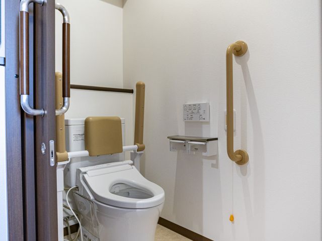 手すり付きトイレ トイレ   手すりが複数設置された、出入りしやすいトイレです。落ち着いた色合いで、使いやすさに配慮されています。