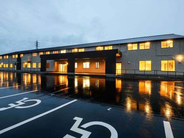 ライトアップされた建物の外観 外観 落ち着いた照明で包まれる夜の佇まいは、利用者やスタッフが安心して過ごせる空間を提供しています。