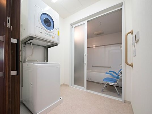 洗濯機と浴室のある洗濯室  