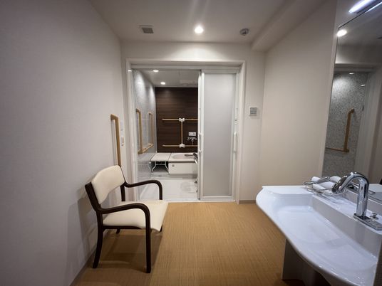 広い洗面台と椅子の浴室