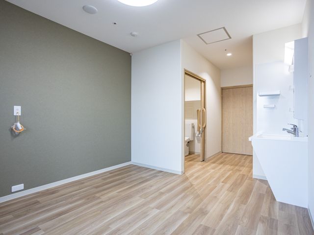 洗面台付き個室の居室 居室   木目調の床と落ち着いた壁色で、すっきりした居室です。洗面台とトイレが近く、使いやすい動線になっています。