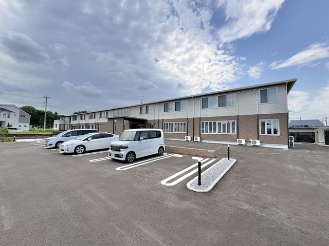 建物外観の駐車場 外観   広い駐車場があり、車での来訪や送迎に使いやすそうです。落ち着いた色合いの建物で、働く場としても安心感があります。