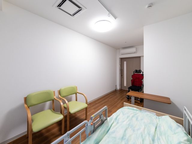 ベッドと椅子の居室 居室   木目調の床と白い壁で、すっきりした印象の居室です。ベッド横に椅子があり、落ち着いて過ごしやすそうです。
