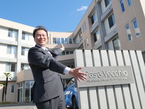 建物を案内する男性と看板の外観  