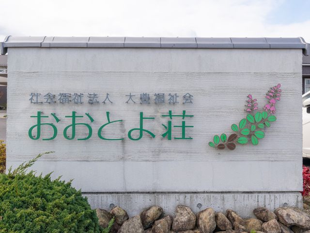 施設の看板 看板 緑に囲まれた看板は、温かみを感じさせます。施設の特徴や雰囲気の一部が垣間見えます。
