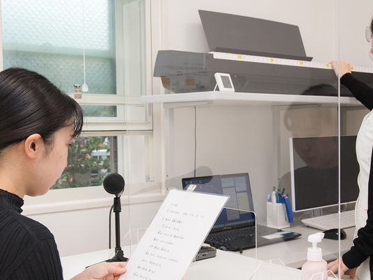 受付で確認する女性とスタッフ  