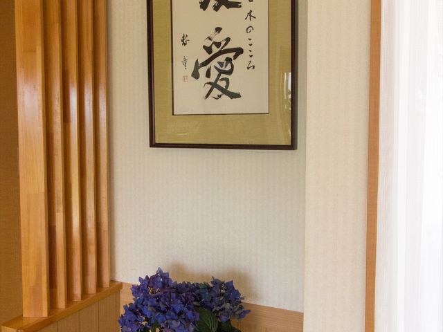 廊下の掲示物と植物 床の間 温かみのある木目調の廊下に、心和む書が飾られており、清潔感のあふれる環境で働ける空間です。