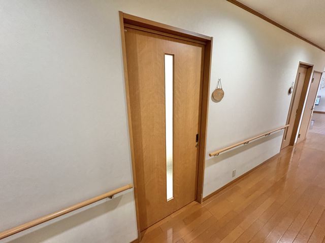 廊下のドア 廊下 滑りにくい床と手すりが備わっており、安全に移動できます。シンプルで整理された空間です。