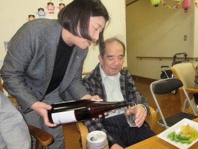 お酒を注ぐスタッフと利用者
