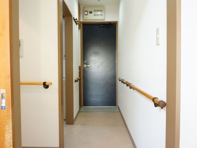 廊下の手すりと扉 居室 手すりが付いた廊下は車椅子や歩行が困難な方も安全に移動できる設計です。明るく清潔なこの空間は、快適な日常生活をサポートします。