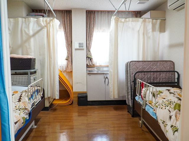 居室のベッドとキッチン 居室 ゆったりした居室には、生活に必要な設備が整っております。快適な個室で、安心して日々をお過ごしいただけます。