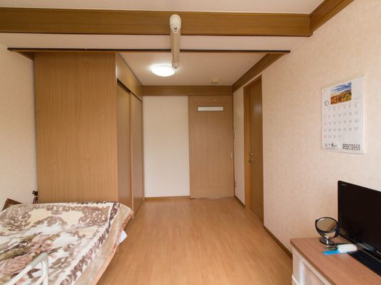 木のぬくもりが感じられるシンプルなワンルームの部屋。扉はスライド式となっており、テレビやベッドが置かれている。