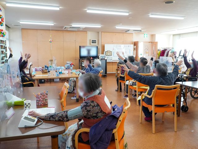 多世代交流の多目的室 共有スペース 様々な活動で利用される広々とした多目的室です。参加者の皆さまは元気に手を挙げ、活動に積極的に参加されています。