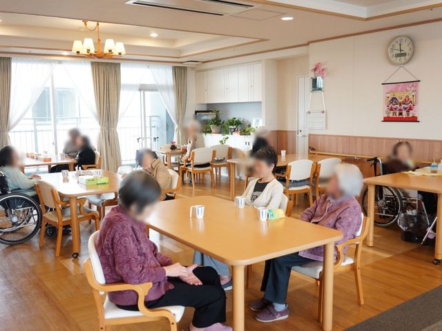 暖かみのある広い食堂 リビング ゆったりとしたテーブルが並ぶ食堂は、落ち着いた雰囲気の中で食事や会話を楽しむ方々で賑わっています。明るく開放的な窓からは自然光が差し込み、和やかな時間が流れています。