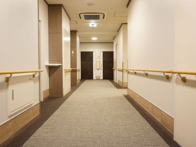 手すり付きの温かみのある廊下 廊下 手すりが備えられ、歩行に不安がある方も安心して行き来できる落ち着いた色調の廊下です。ゆったりとした通路はゆとりのある生活空間を提供します。