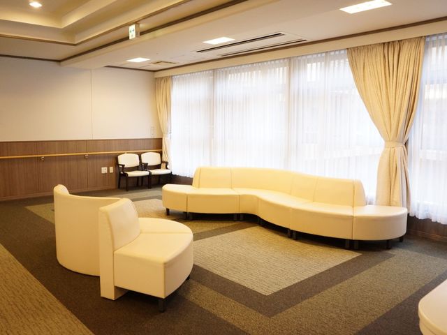快適な共有ラウンジ空間 多目的ホール 落ち着いた色合いの大型ソファが配置された開放的なラウンジです。日差しが差し込む窓際で、ゆっくりとおくつろぎいただけます。