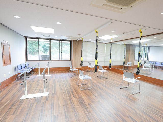 広々とした機能訓練室 機能訓練室 床は木目調で、各種バーを使って体を支えながら歩行練習ができるスペースが整っている。