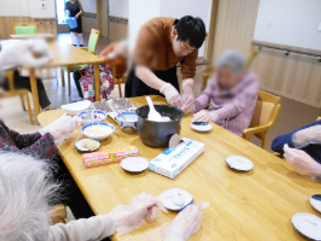 調理中のダイニング ダイニングルーム 自然光の中で、居住者の方々が料理の準備を楽しんでいるスペースです。リラックスした交流の場です。