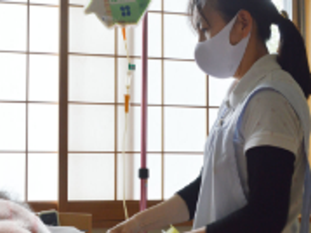スタッフ作業中の居室 居室 自然光が入る居室で、スタッフが丁寧に作業を行っています。安らぎの環境が整っています。