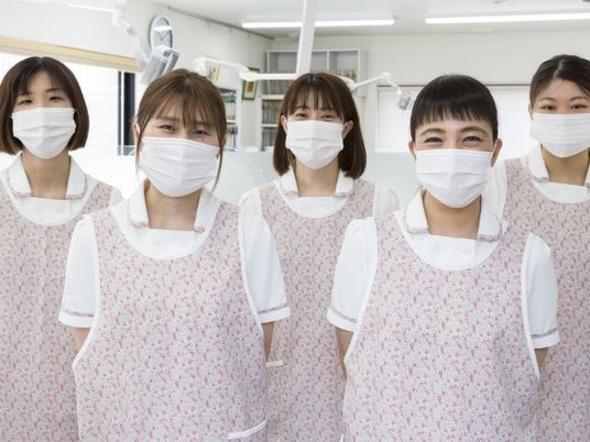 マスク姿のスタッフが並ぶ室内  