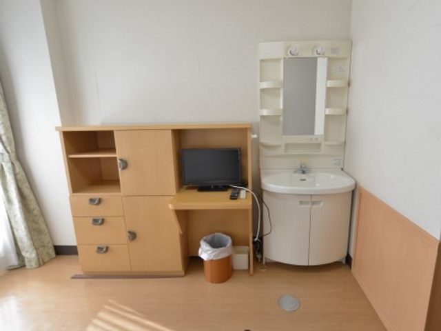 居室内の家具と洗面台 収納 機能的な家具と照明付き鏡が備えられた清潔な居室です。明るく快適な空間でのびのびとお過ごしいただけます。
