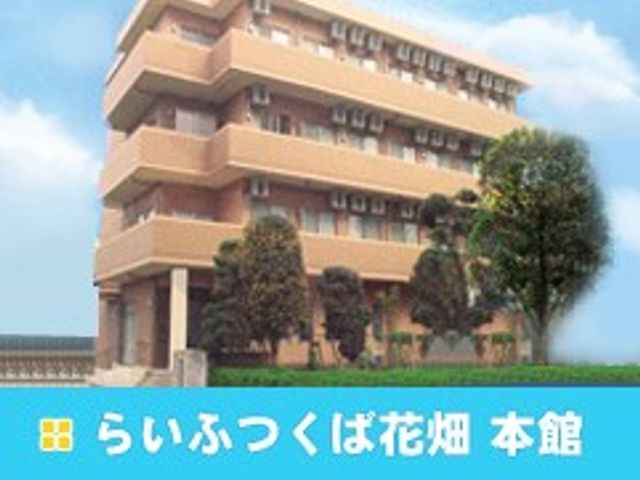 らいふつくば花畑 本館外観 外観   ベージュ系の外壁が印象的な、落ち着いた雰囲気の建物です。周囲に木々があり、穏やかな環境で働けそうです。