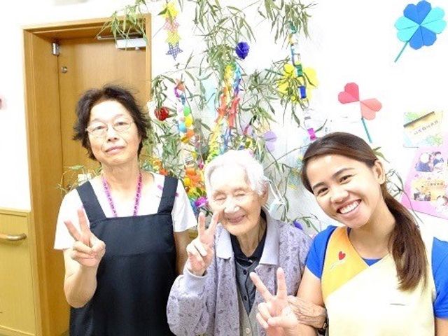 楽しげな三人のスタッフイメージ イベント 笑顔でピースサインをするスタッフの姿が、温かな職場の雰囲気を伝えています。ご高齢の方々と共に楽しい時間を過ごしている様子が見て取れます。