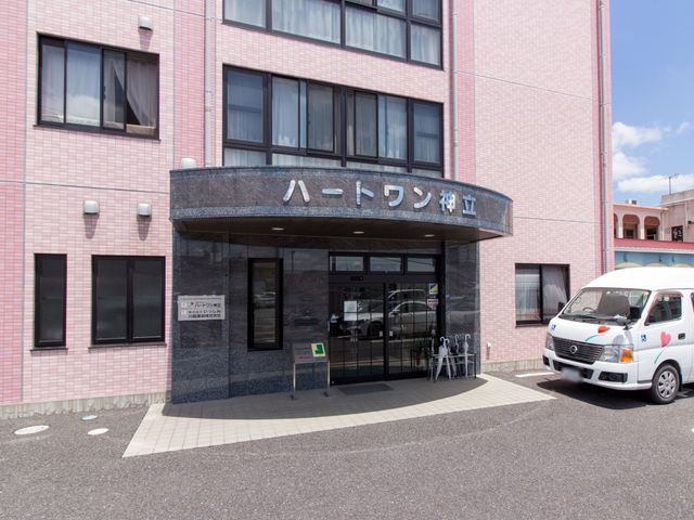 ピンクの壁の建物エントランス 出入口 広々としたエントランスは清潔感があり、明るい印象を与えます。アクセスしやすい場所に位置しており、安心してご利用いただけます。