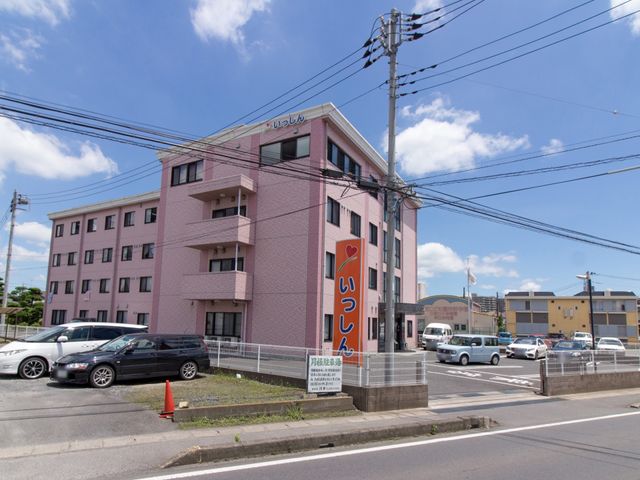ピンク色の建物の外観 表示板 落ち着いた色調の建物が目を引きます。通勤しやすい立地条件を備えており、日々の業務に集中できる環境です。