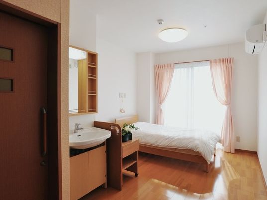 明るい居室のベッドと洗面台  