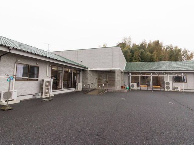 白い壁の建物と駐車場 玄関  ゆとりのある空間が確保された建物の外観です。働く環境の一端をこの光景から感じ取っていただければ幸いです。