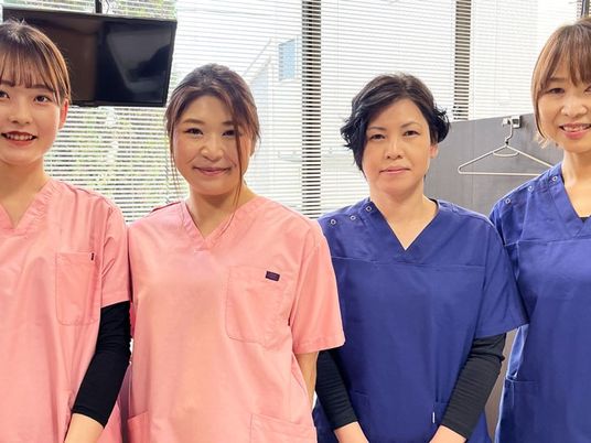 笑顔のスタッフが並ぶ室内  