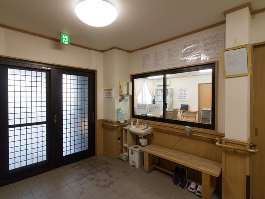 玄関を入ったところにある玄関ホール。手すりを完備しており、ベンチや手洗い場なども設置されている。壁にある窓からはスタッフルームが見える。