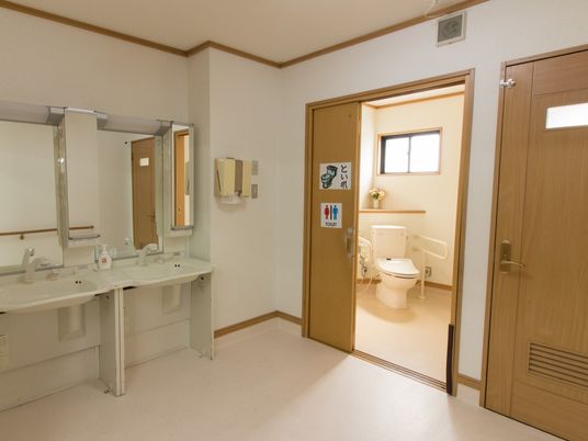 トイレのすぐ横に洗面台が設置されている。洗面台は白を基調としたデザインで、大きな鏡や照明もついている。