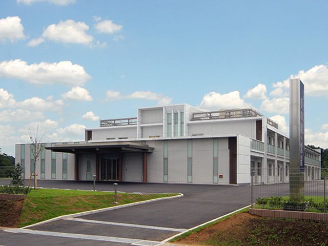 青空の背景に建物 外観 緑に囲まれた静かな環境の中にある、開放感あふれる建物の外観です。