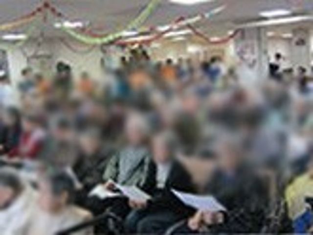 集会の様子 多目的室 多くの人々が集まり、活動を楽しむための広々とした空間です。天井には飾りがあり、イベントが行われています。
