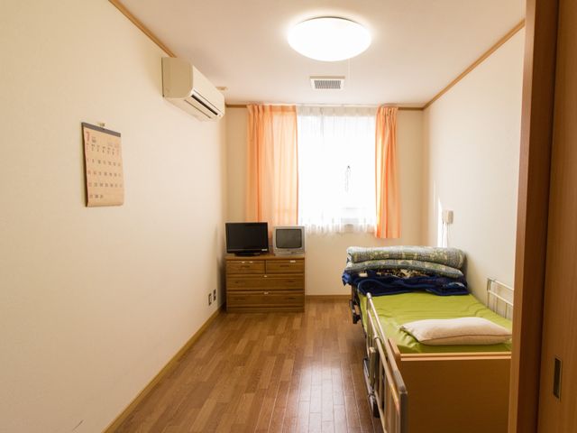 居心地の良い清潔な居室 居室 落ち着いた色合いの居室は、必要な家具が整い、快適な生活を支えます。窓からは自然光が差し込み、暖かな雰囲気を醸し出しています。