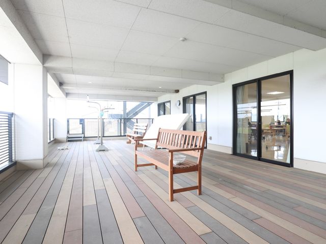 明るい広々としたテラス バルコニー 木製のベンチが置かれた開放的なスペースは、ゆったりとした時間を過ごせる場所です。外の景色を眺めながら、潤いのある日々をお過ごしいただけます。