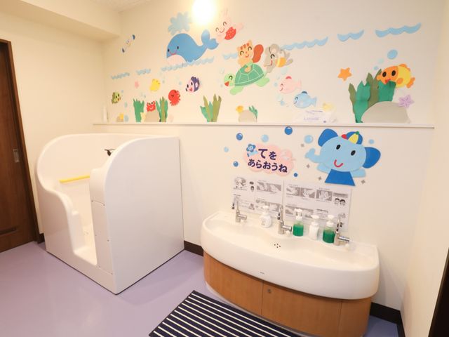 カラフルな壁装飾の洗面台 洗面台 明るく楽しい壁画が描かれた洗面スペースで、日々の清潔を保つ工夫がされています。利用者の笑顔を引き出すデザインです。