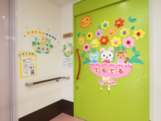 カラフルな壁飾りの廊下 保育園 廊下にはカラフルで元気な印象を与える壁飾りがあり、訪れる方々へのあたたかい歓迎の意を表しています。安全に配慮された手すりもしっかりとあります。