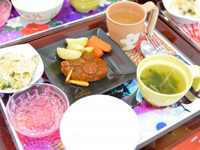 多彩な料理が広がるテーブル 食堂 色とりどりの食器に盛られた栄養バランスの取れた食事が並んでいます。職員の方も準備のしやすい環境です。