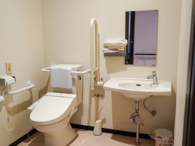 バリアフリートイレ設備 トイレ サポート用の手すりが備わった清潔なトイレです。必要なときに安心してお使いいただける環境が整っています。