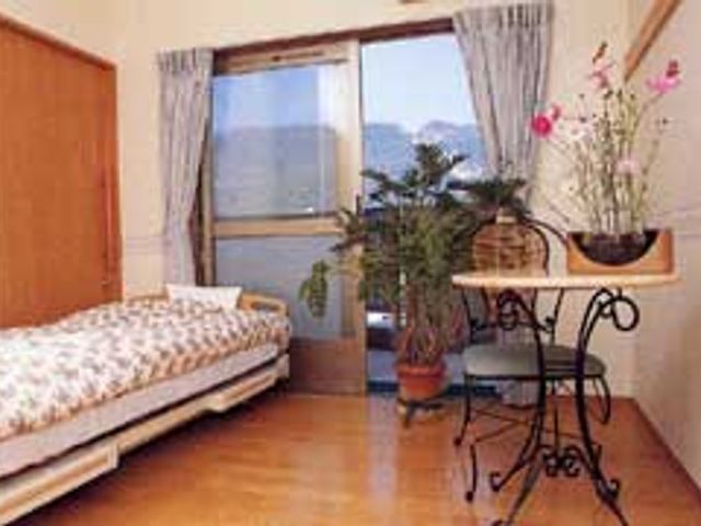 自室ベッドと花のある部屋 居室 広々としたプライベートな空間で、窓から自然光が差し込む居室です。快適に過ごせます。