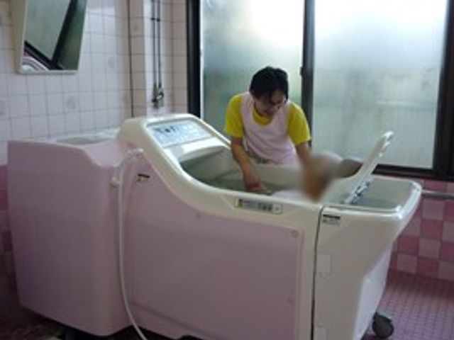 作業中のスタッフがいる浴室 浴室 光が差し込む中、スタッフが入浴ケアを行っています。明るい環境で作業ができます。