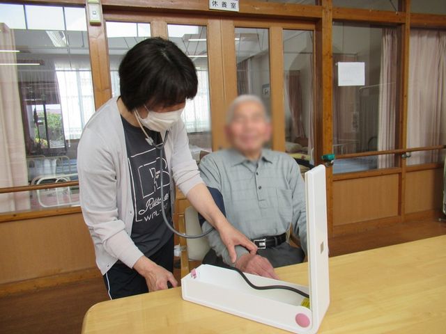 職員と利用者の様子 機能訓練室 職員が利用者の状態を確認しています。和やかな雰囲気で、安心して働ける環境です。