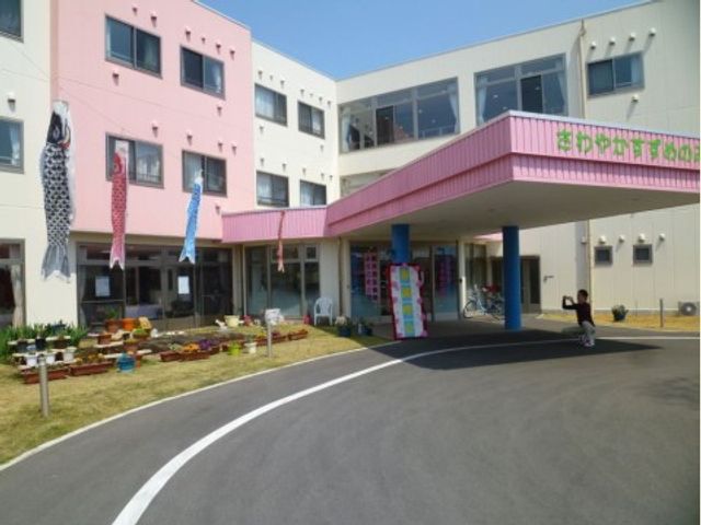 カラフルなエントランス施設 外観 ピンク色の屋根が印象的な施設入口です。エントランス前には植物が並び、訪れる人を温かく迎えています。