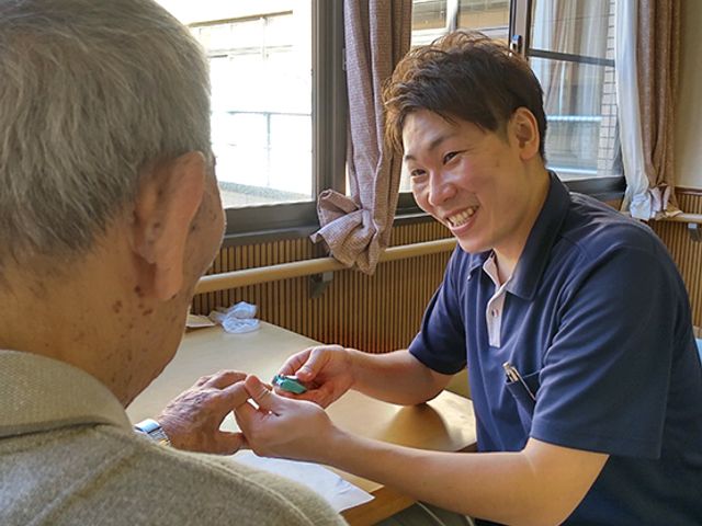 笑顔のスタッフエントランス エントランス 明るい窓辺では、スタッフが利用者と親しげな交流をしています。笑顔が溢れる空間です。