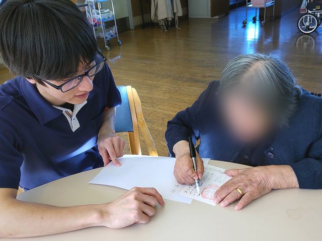 スタッフとの交流中の室内 ラウンジ 会話を楽しみながら、快適なラウンジで手紙を書く時間を過ごせます。利用者同士の良い交流の場です。