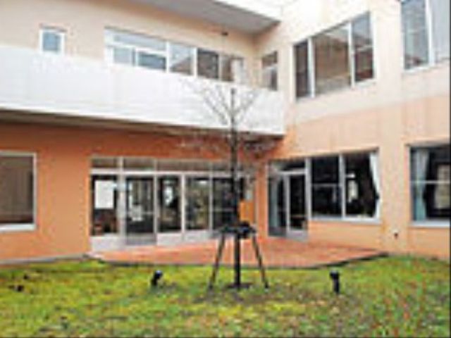 白と橙の明るい中庭 中庭 橙色の壁が印象的な開放的な中庭です。職員とご利用者が心地よい時間を共有するためのスペースが確保されています。
